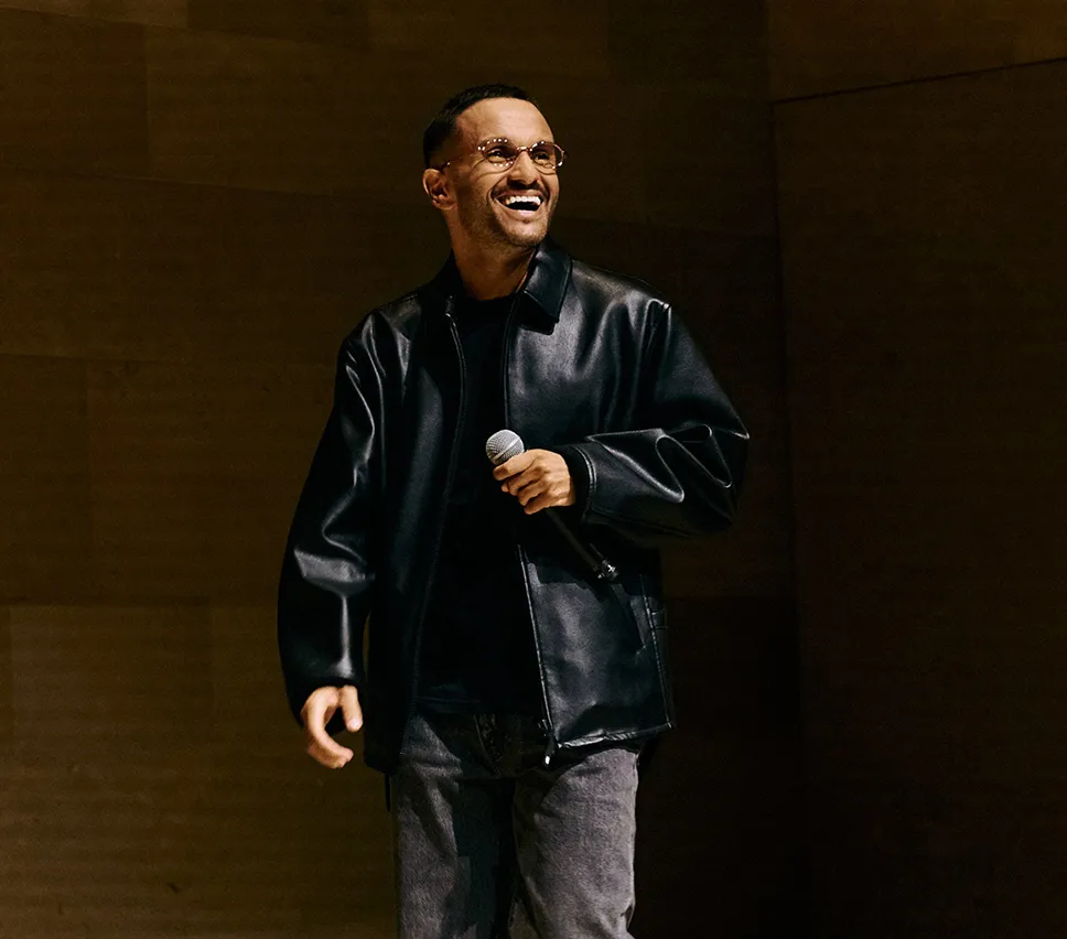 Man holding microphone on stage, smiling brightly