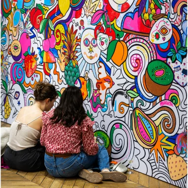 Two women coloring vibrant mural wall art