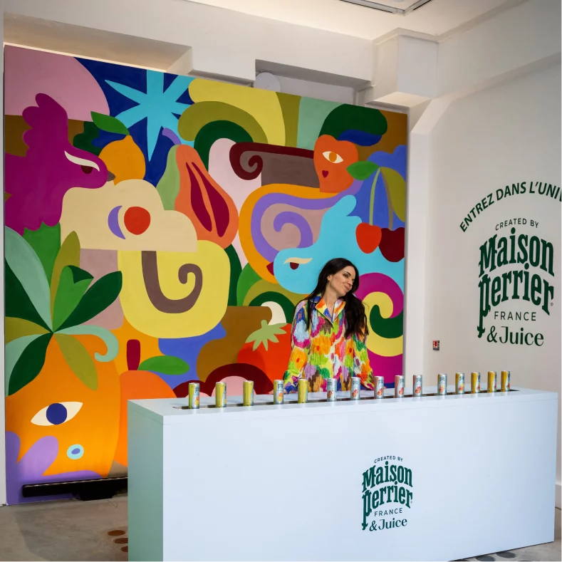 Woman standing before colorful mural and juice display