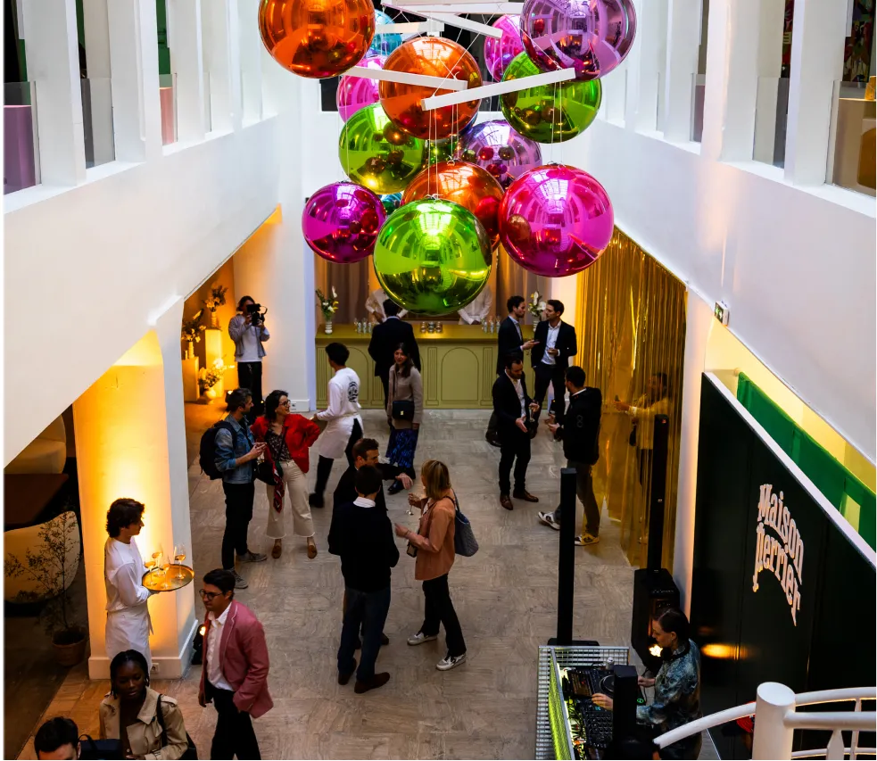 Guests mingle beneath colorful hanging spheres indoors