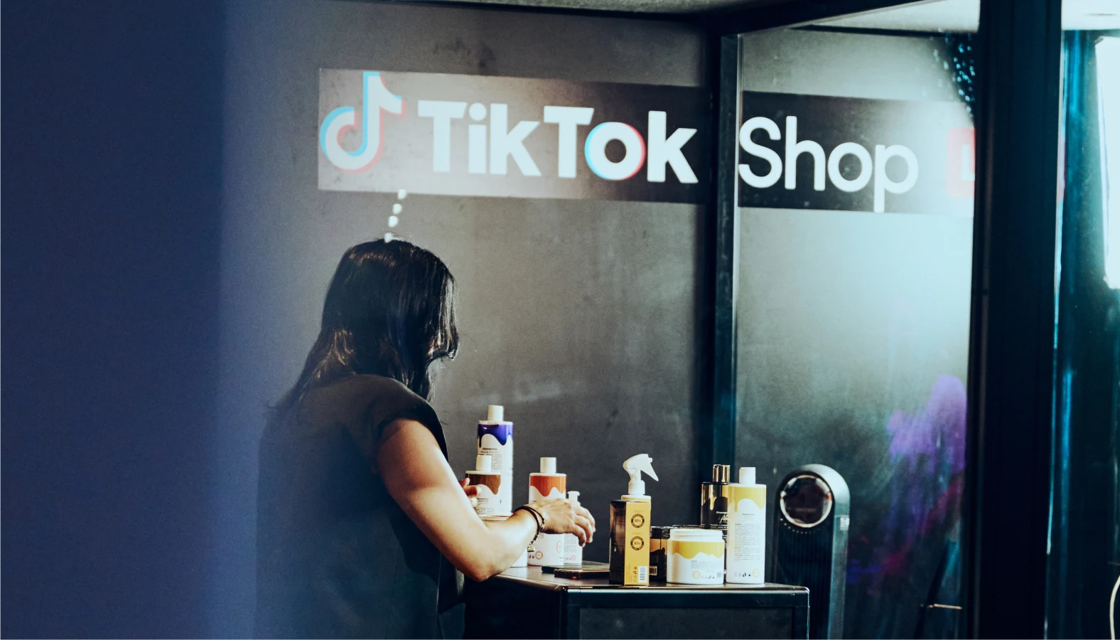 Person arranging products under TikTok Shop sign